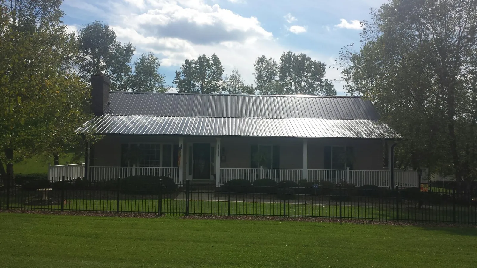 Gray metal roof on a brick ranch with a full width front porch — Gutter Guard Installation work by our crew in Waynesboro